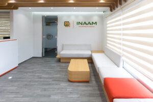 Salle d'attente moderne chez Inaam avec des sièges confortables en bois, un décor minimaliste, et un éclairage naturel abondant.