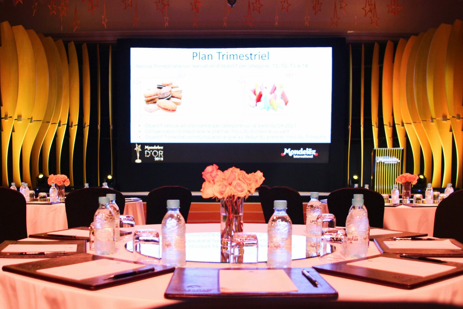 Vue rapprochée d'une table élégamment décorée avec des fleurs et de l'eau minérale, lors de la présentation du plan trimestriel de Mondelez