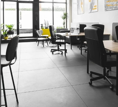 Espace de travail en open space avec un sol en béton, des chaises ergonomiques et des bureaux modernes, favorisant la collaboration et la productivité.