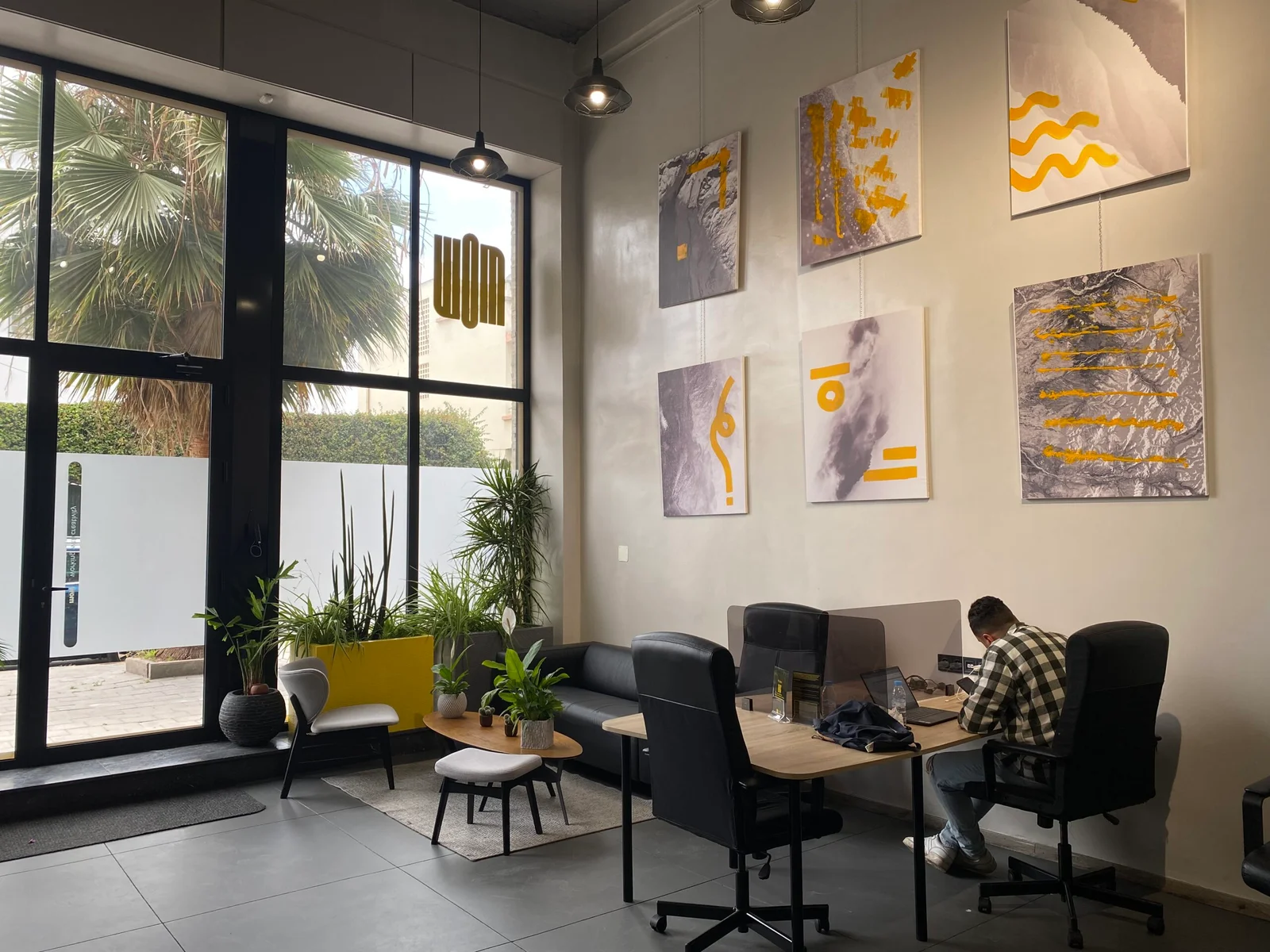 Un espace de coworking moderne intégrant des éléments biophiliques avec des plantes et des œuvres d'art abstraites sur les murs, créant un environnement apaisant et inspirant pour les professionnels.