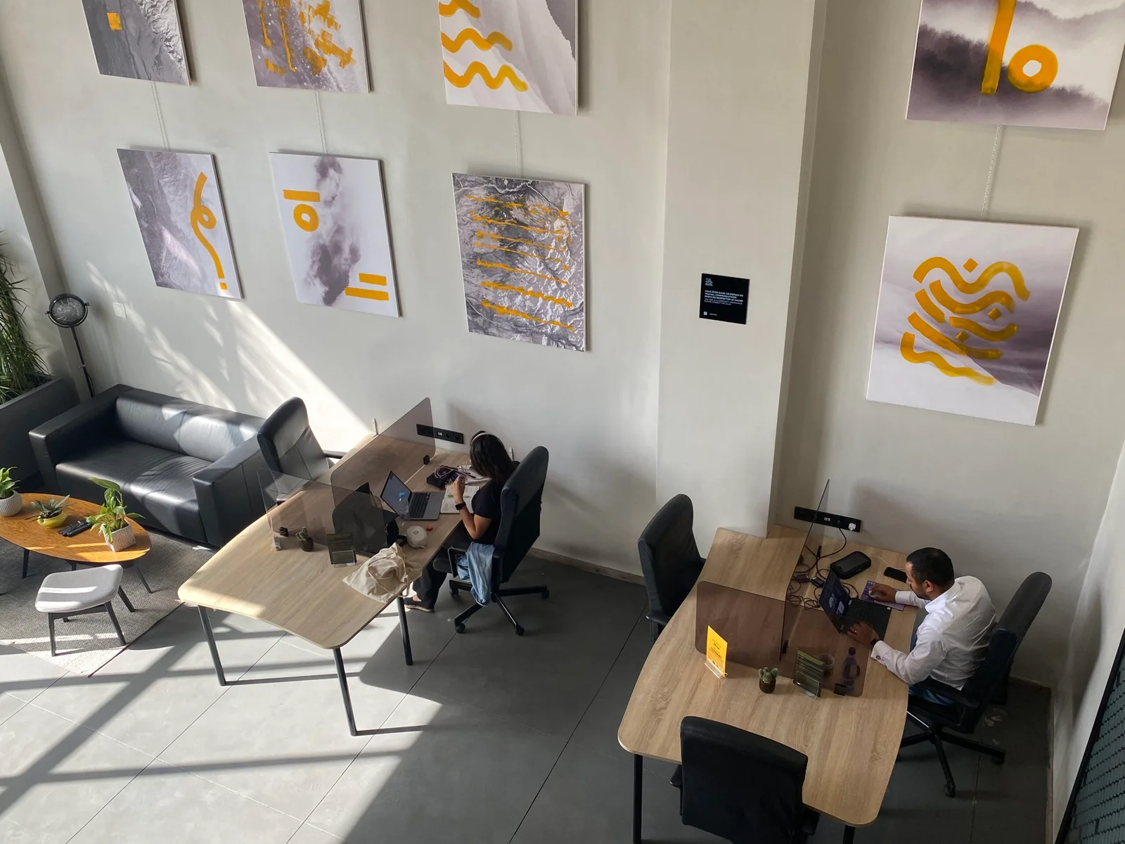 Espace de travail lumineux au MOW® coworking, avec des œuvres d'art moderne et des postes de travail aménagés