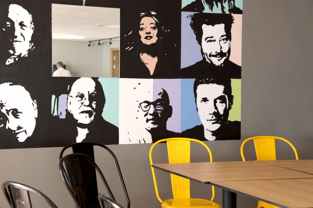 Mur décoré avec des portraits en noir et blanc de personnes célèbres, avec des arrière-plans colorés, ajoutant une touche artistique à l'espace