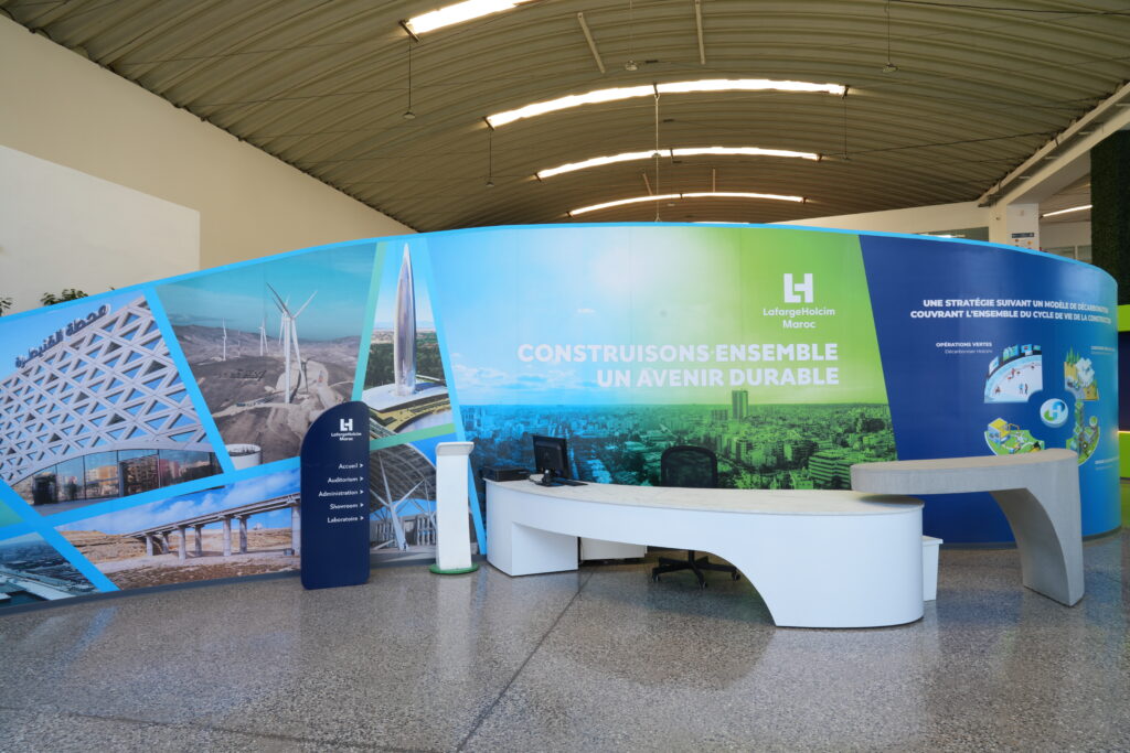 Stand de LafargeHolcim Maroc affichant le slogan 'Construisons ensemble un avenir durable' avec des images d'infrastructures et de projets