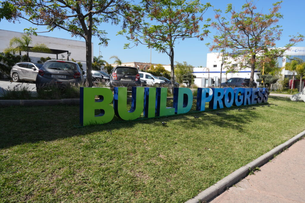 Slogan 'Build Progress' dans les jardins de LafargeHolcim Maroc, symbolisant l'engagement pour le progrès durable