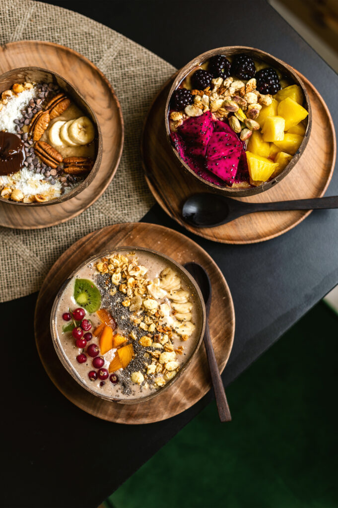 Trois bols d'açaï colorés avec des fruits frais, granola et noix, servis chez GAIA Juice