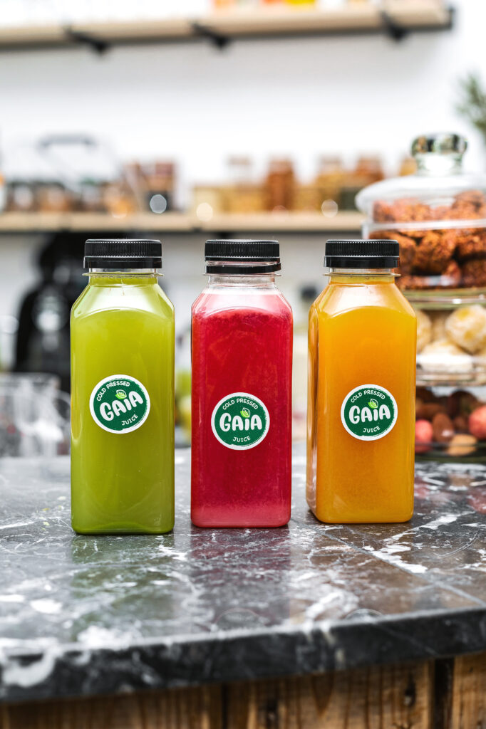 Trois bouteilles de jus pressés à froid GAIA Juice aux couleurs verte, rouge et orange