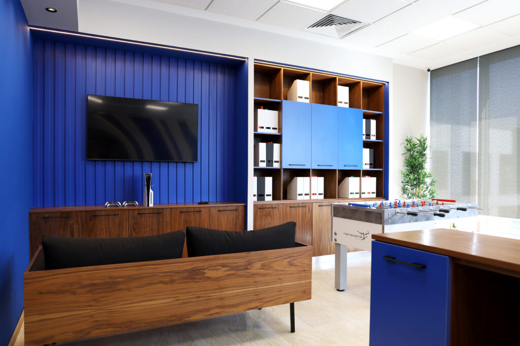 Intérieur du bureau chez Tounina Consulting, mettant en avant un canapé moderne, un mur bleu avec télévision, et des rangements élégants pour documents, accompagné d'une table de baby-foot