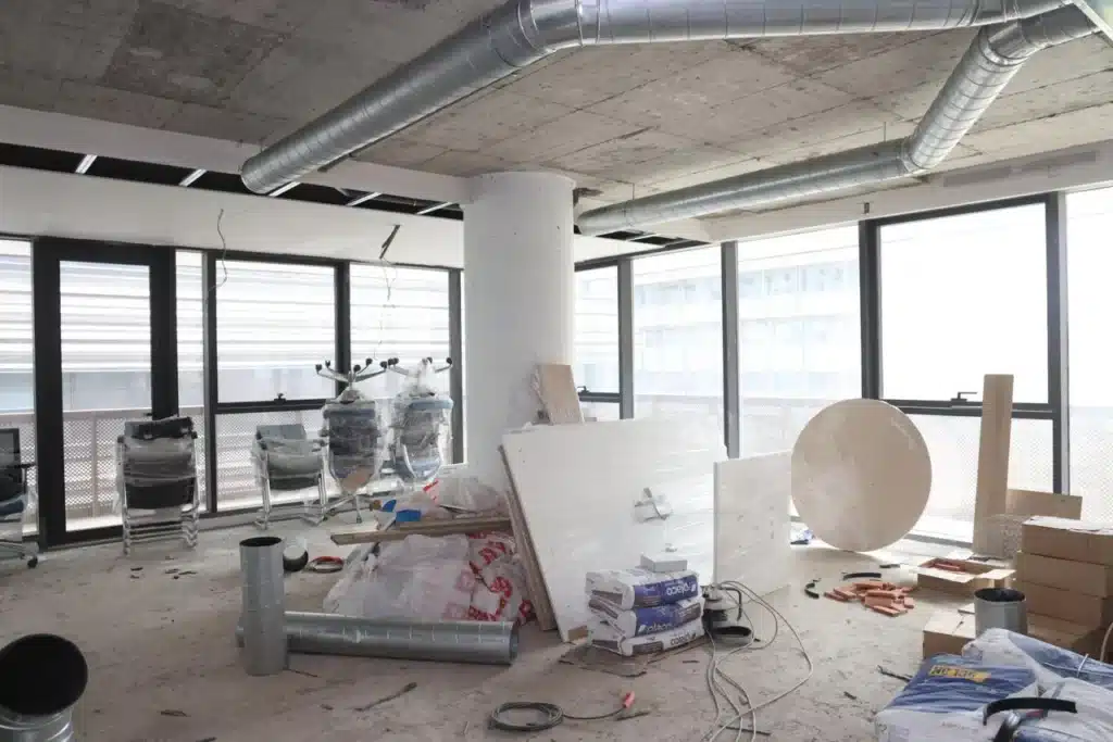 Stockage de matériaux de construction, mobilier de bureau emballé et gaines techniques sur un chantier en cours.